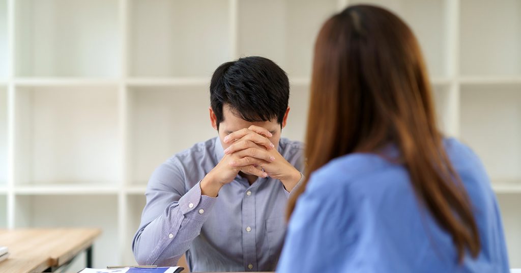 Stressed man experiencing burnout during office meeting
